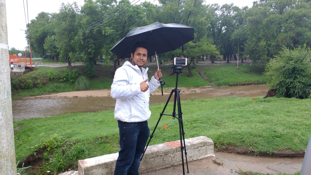 Photo of Sujan Pal taking videos of the river flow during RELAMPAGO to measure streamflow, using the LSPIV method.
